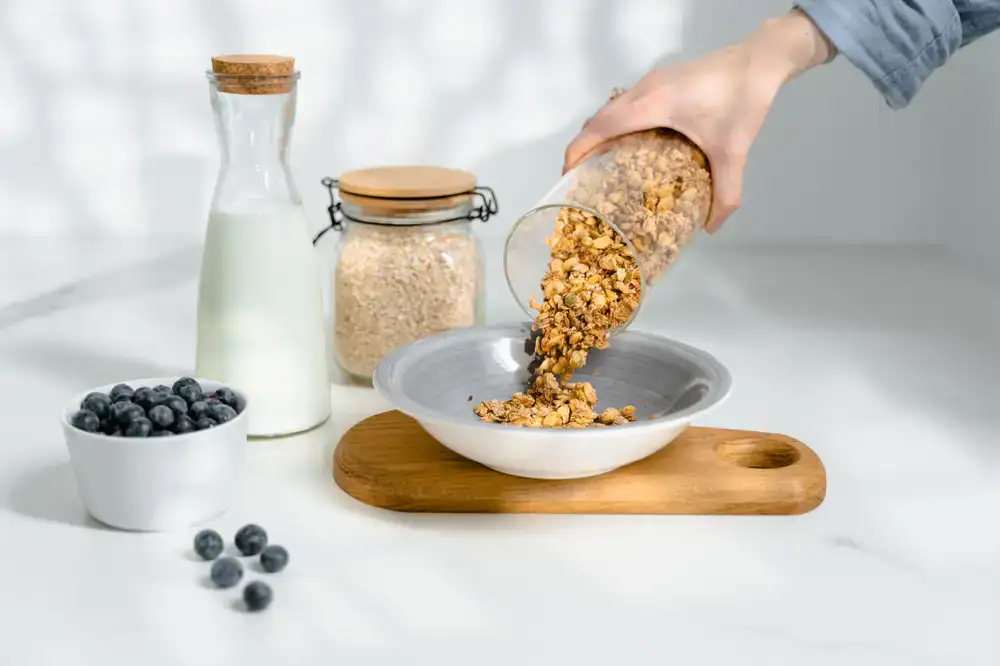 Pouring oats from a gravity bin into a container